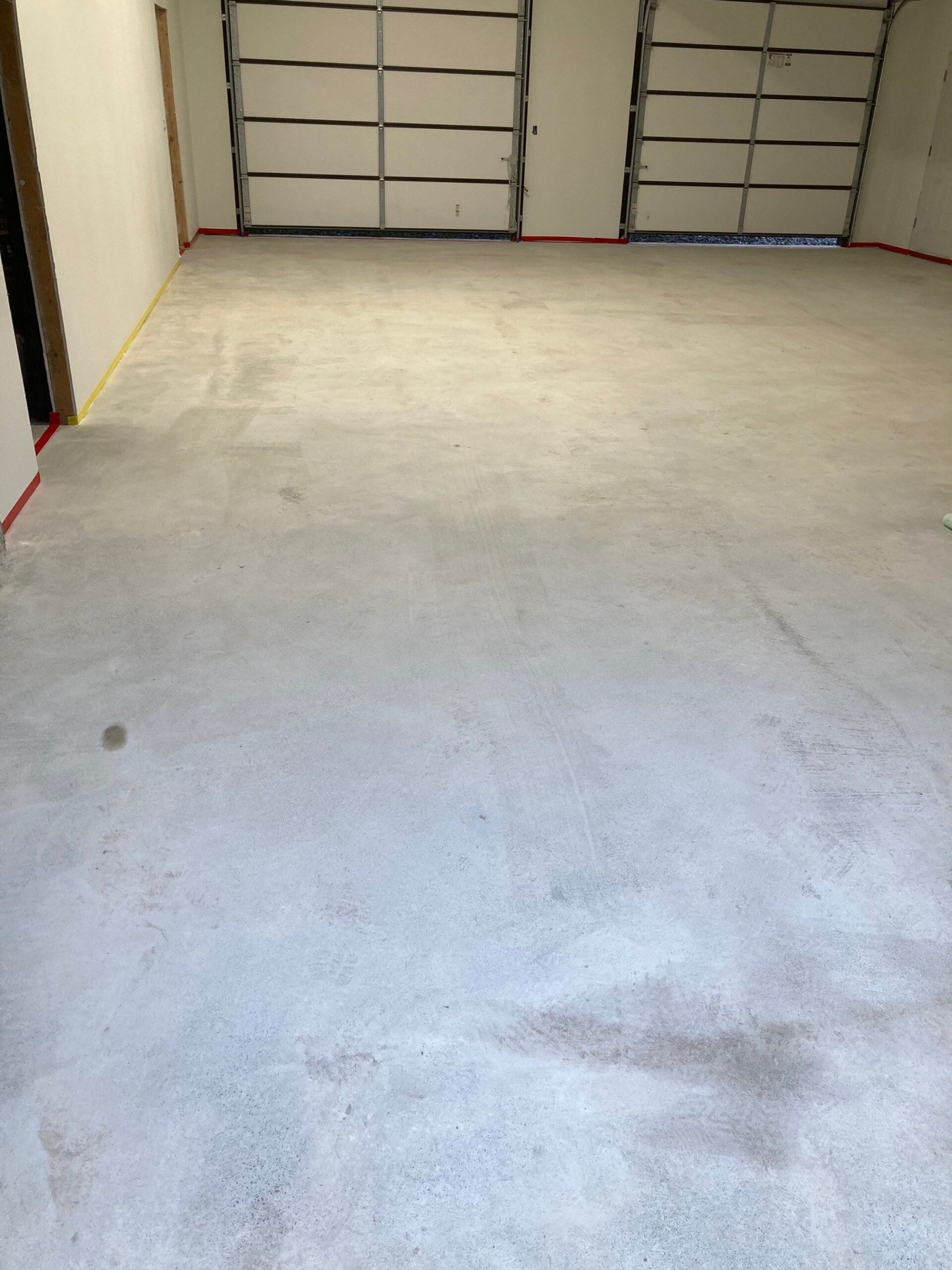 A garage with two garage doors and a concrete floor.