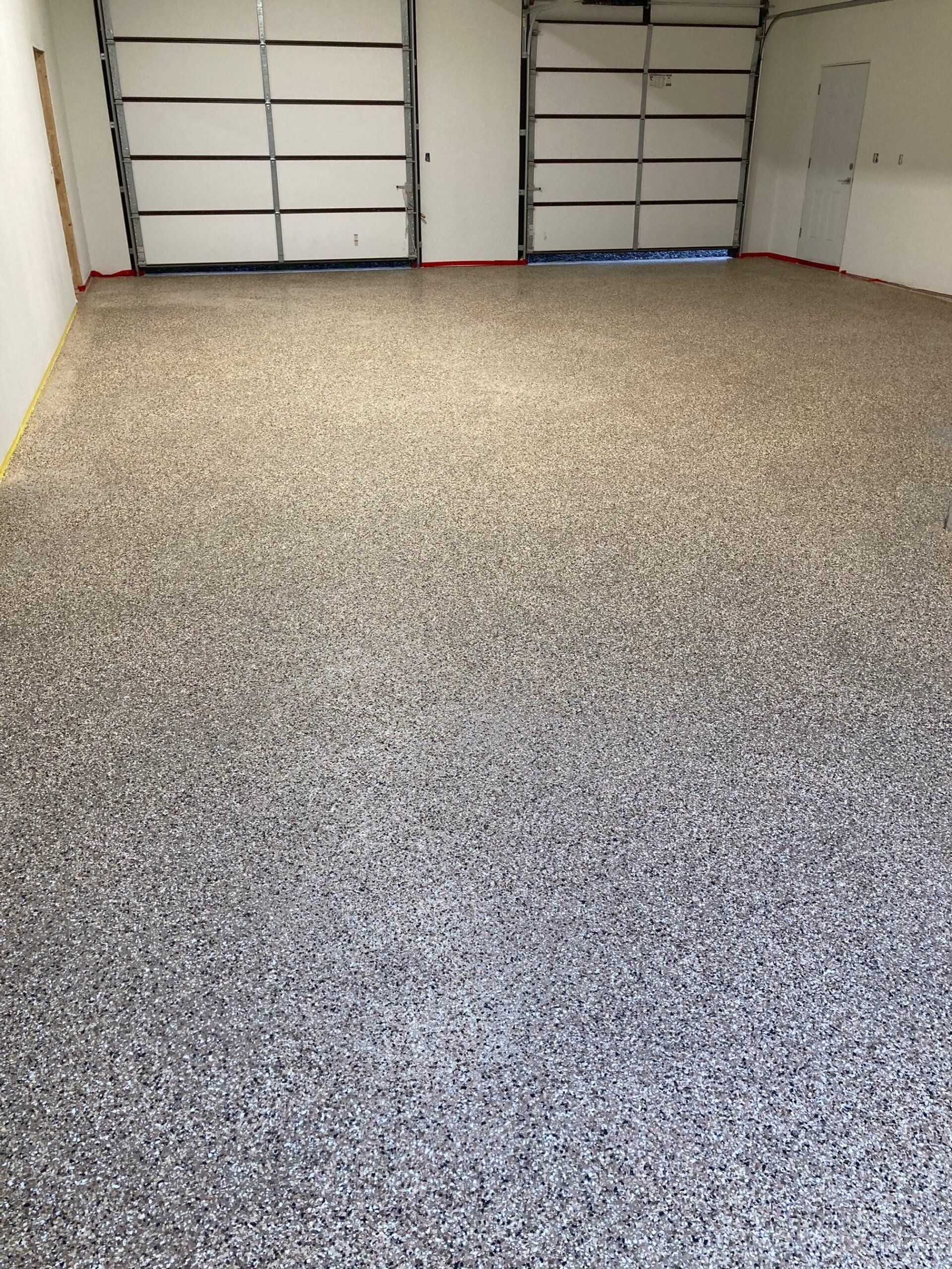 Garage with epoxy speckled flooring and two closed garage doors.