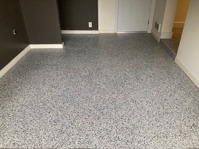 Gray speckled epoxy floor in a room with dark and white walls.