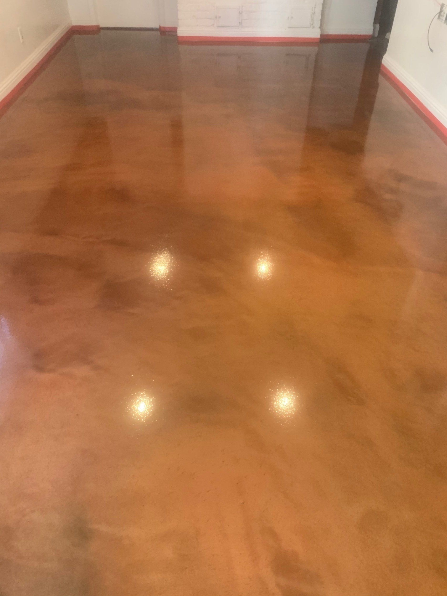 A shiny concrete floor in a room with a red trim.