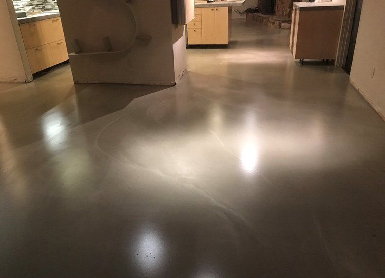A kitchen with a shiny concrete floor and wooden cabinets.
