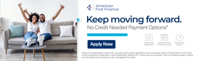 A man and a woman are sitting on a couch with their arms in the air.