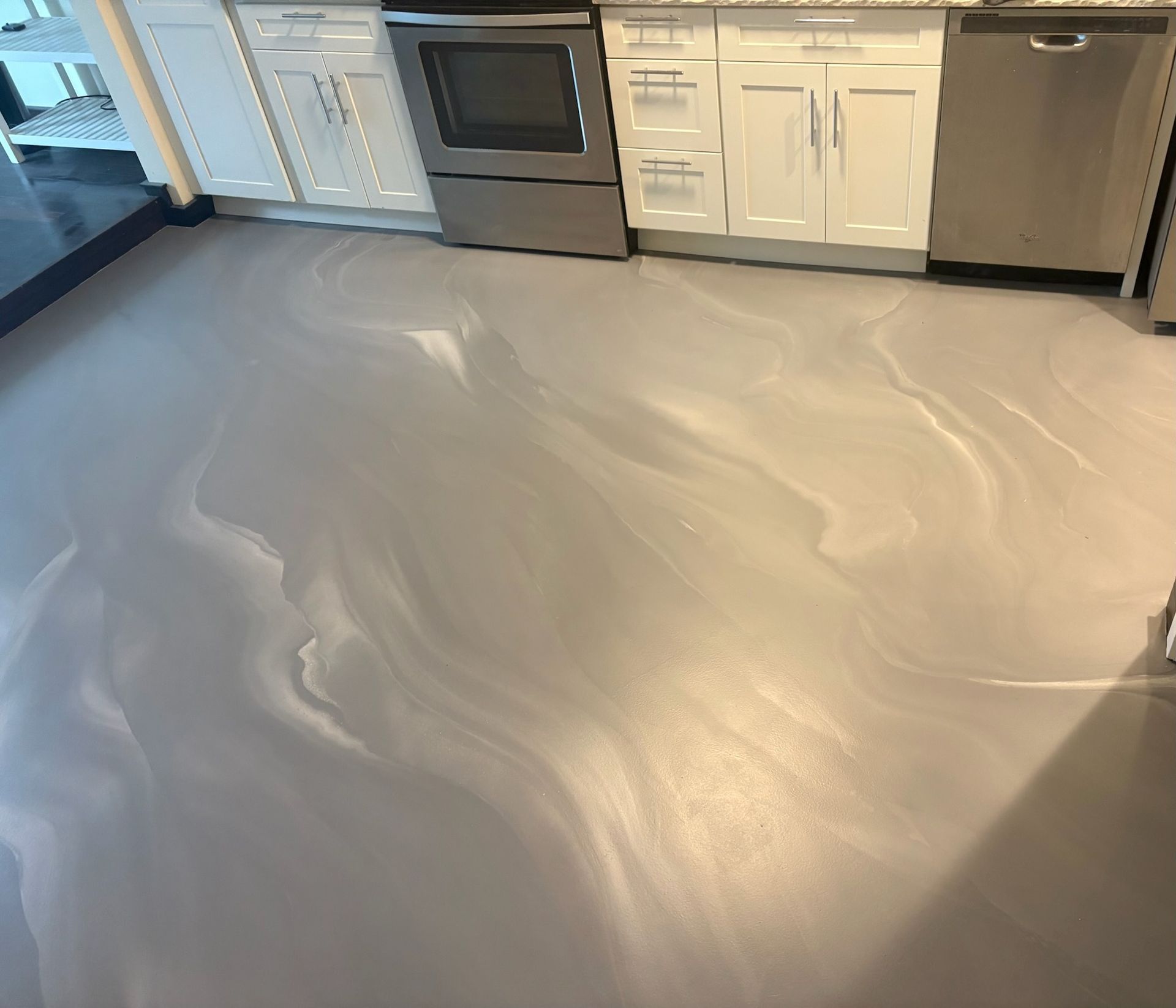 Freshly coated light gray kitchen floor with white cabinets and stainless steel appliances