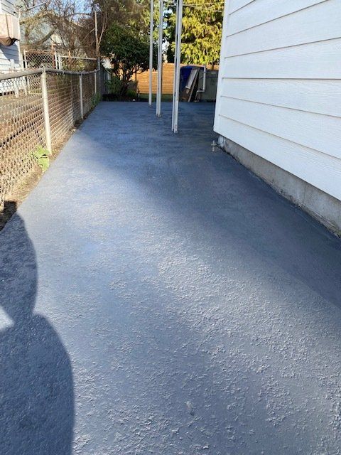 A driveway leading to a house with a fence in the background