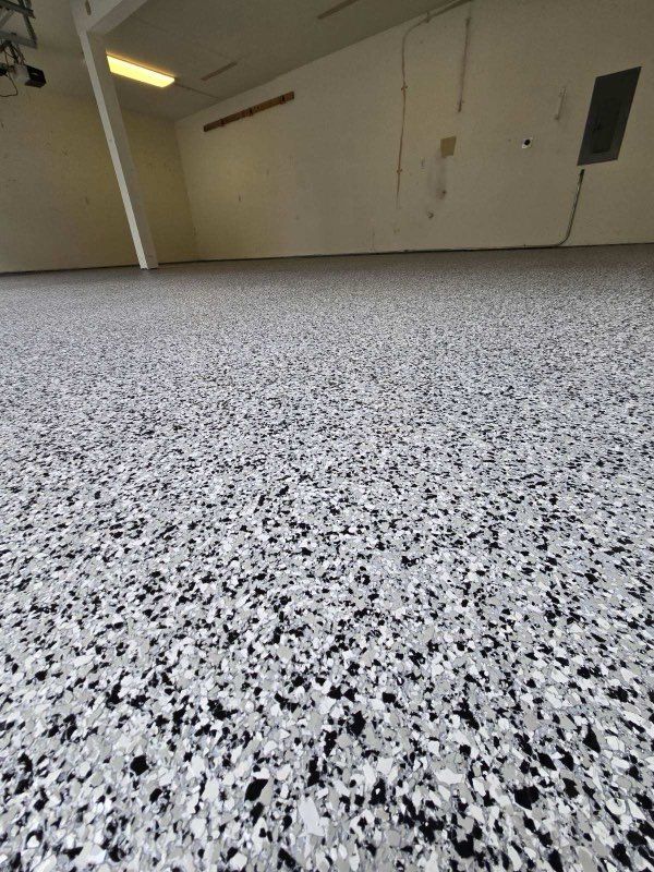 Low-angle view of a speckled terrazzo floor in an empty room with beige walls and a window high on the wall