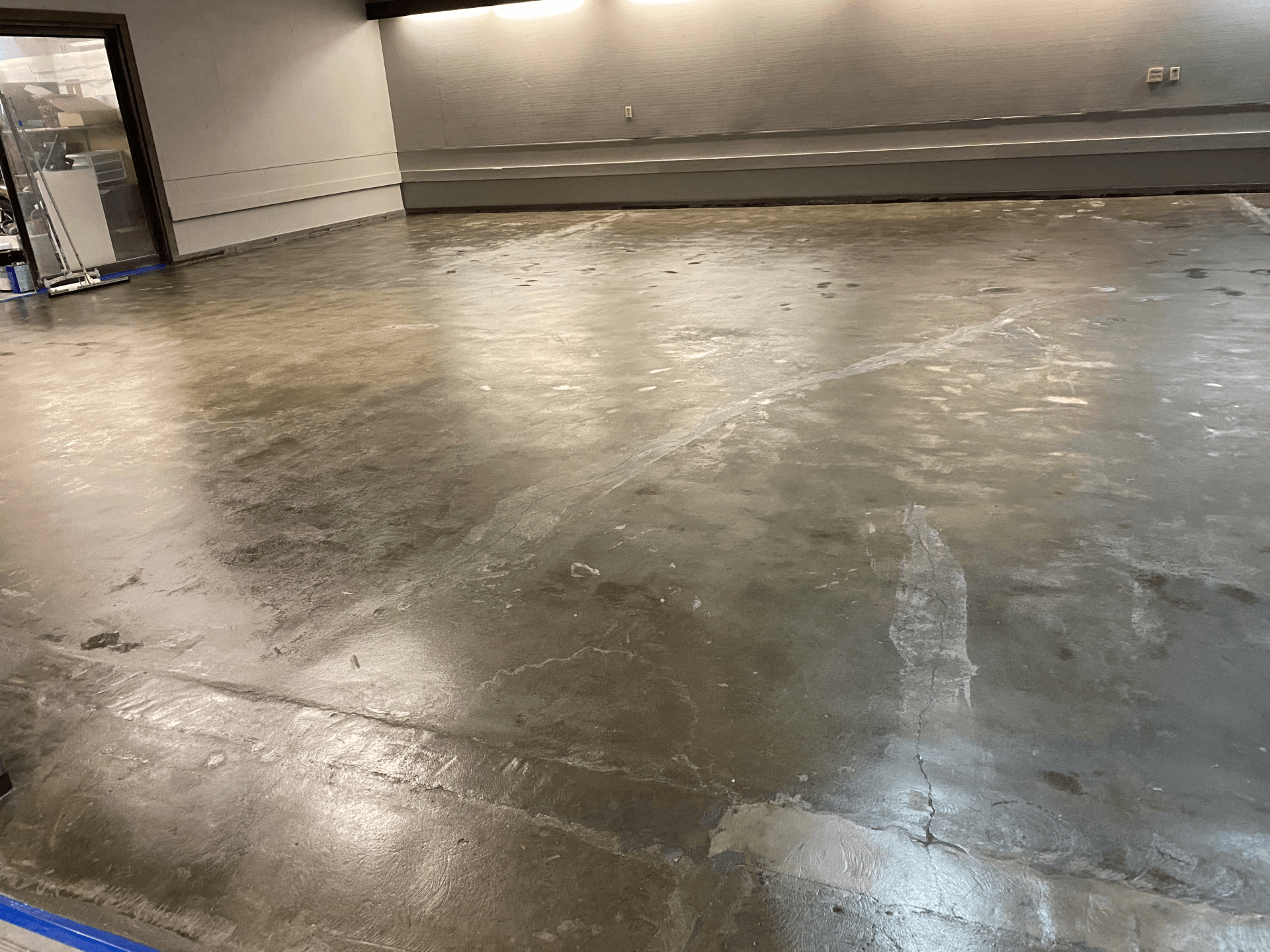 A dirty concrete floor in a room with a door.