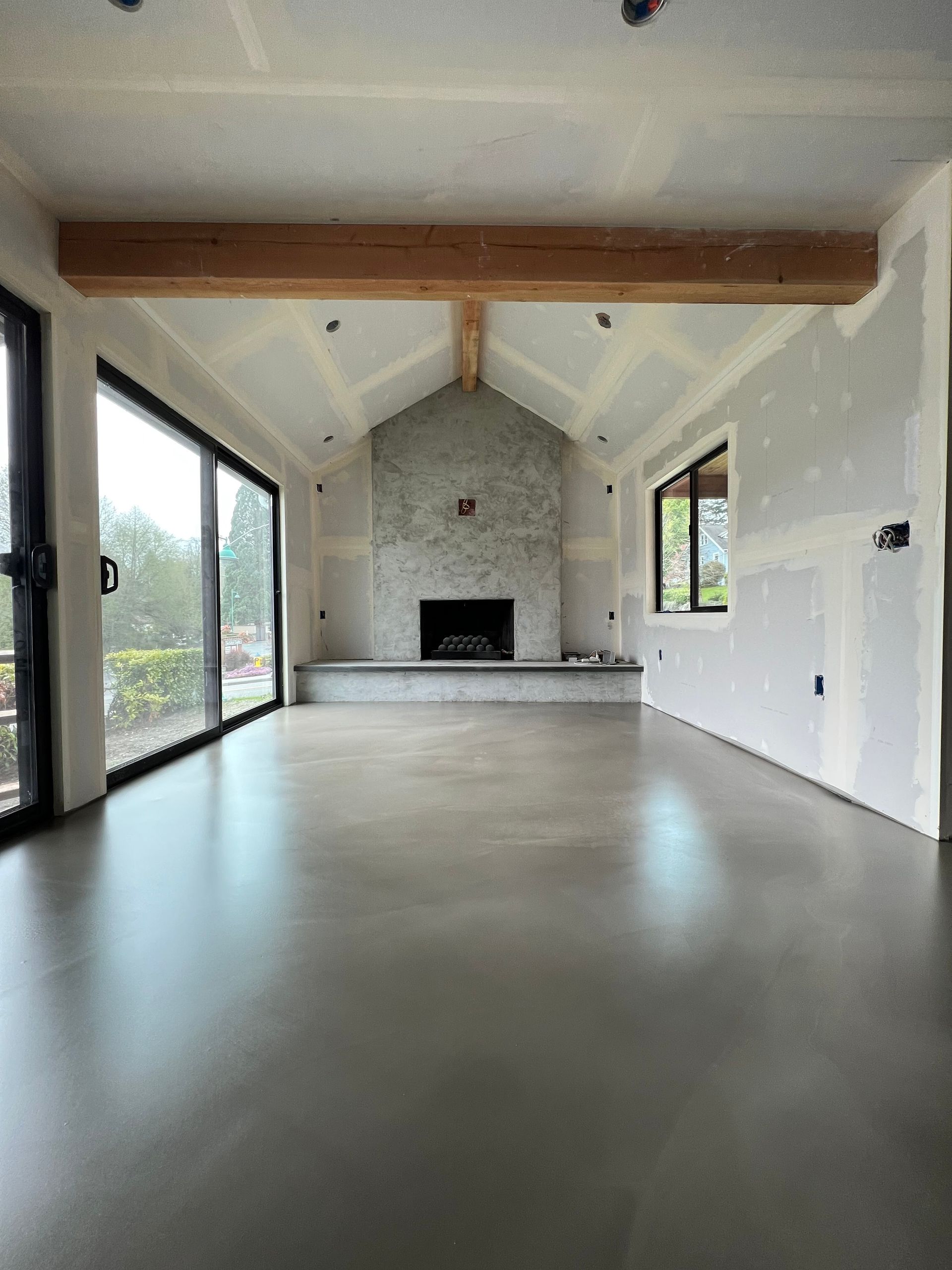An empty living room with a fireplace and sliding glass doors.