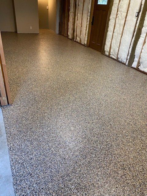 Speckled epoxy floor in a hallway with unfinished wall and a door.