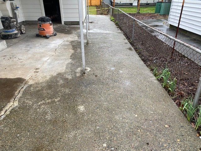 A concrete walkway next to a chain link fence and a vacuum cleaner.