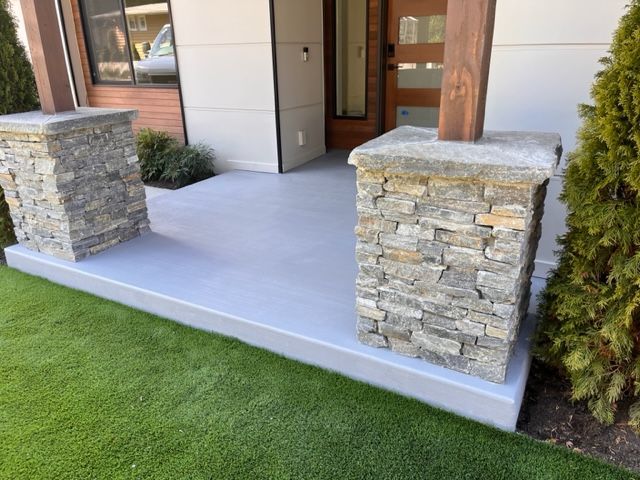 A concrete porch with stone pillars in front of a house.