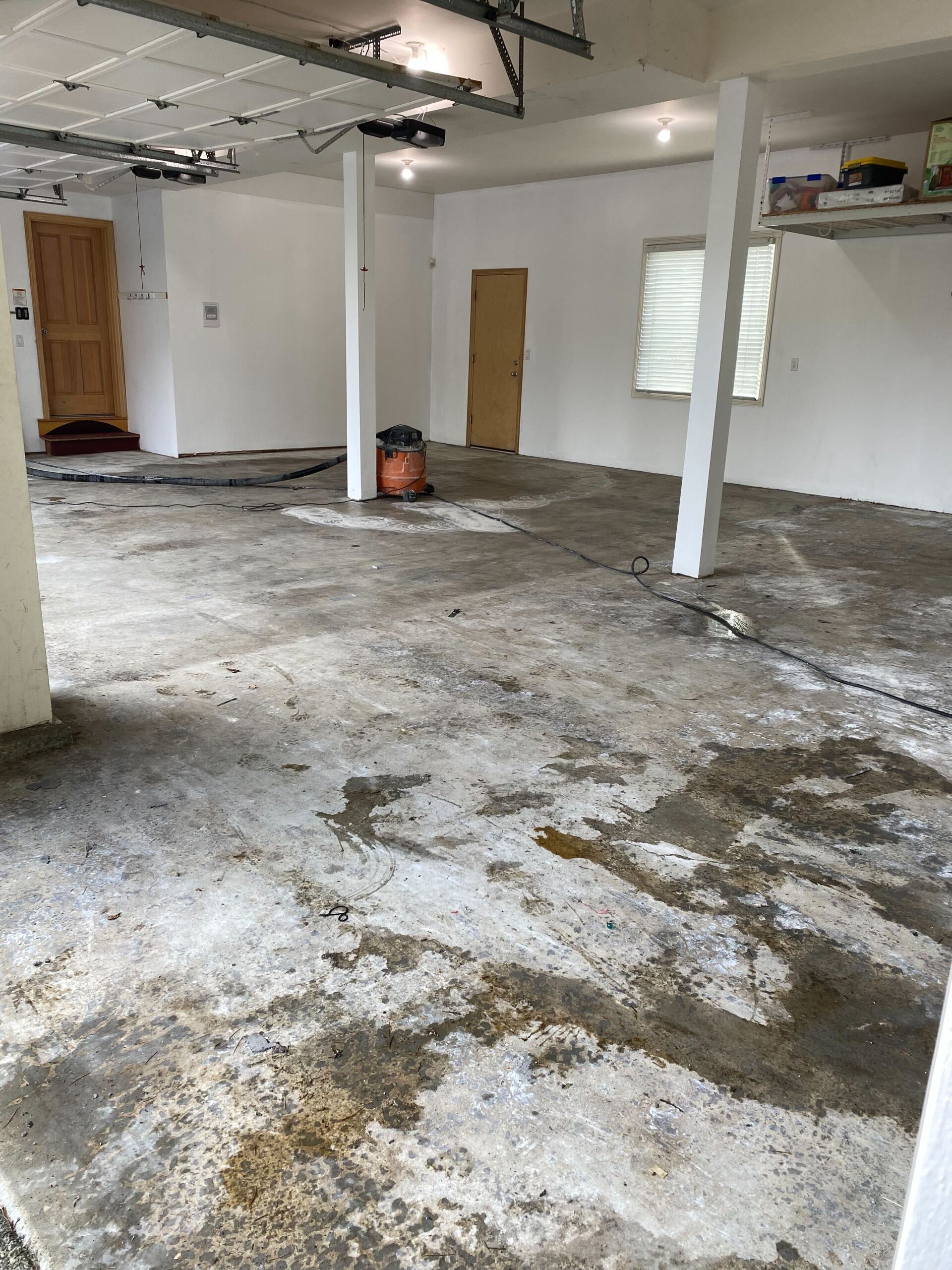 A garage with a dirty concrete floor and white walls.
