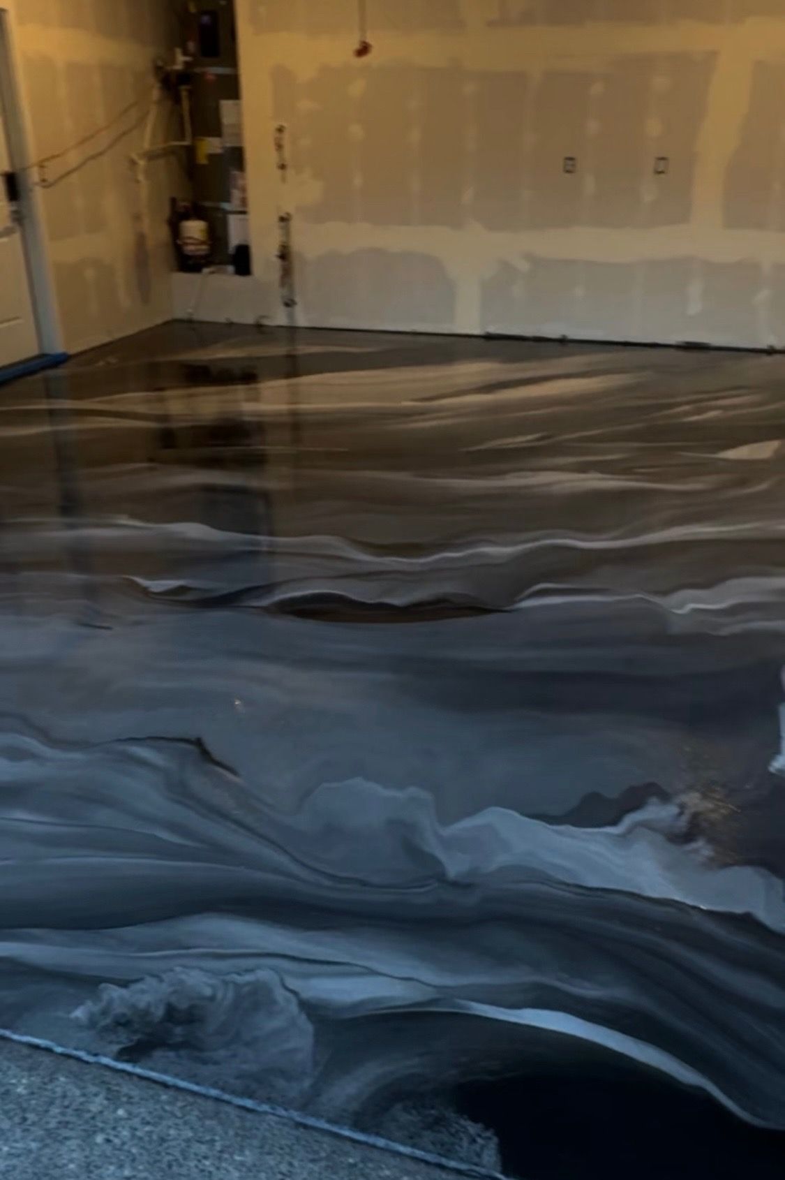 Black and silver epoxy floor in an unfinished room, swirled pattern.
