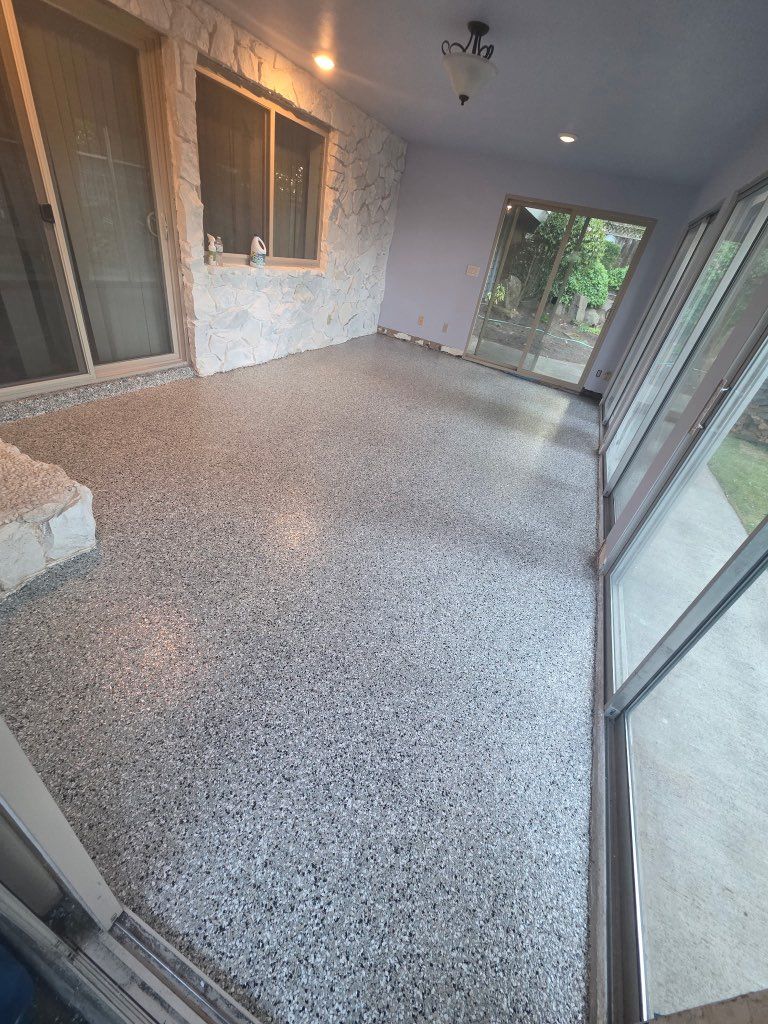 Small covered patio with terrazzo floor, sliding glass door, windows, and a view of greenery outside