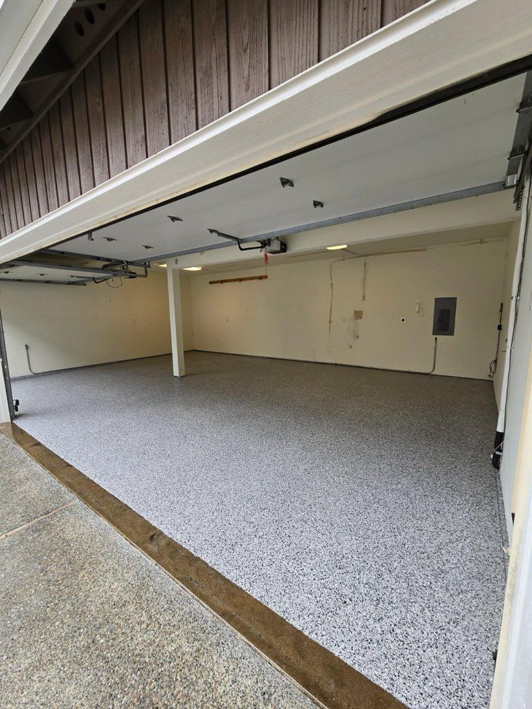 Open garage with speckled epoxy floor and beige walls under a raised door