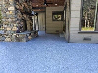 Blue concrete patio with fireplace and house exterior.