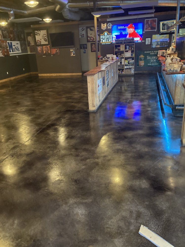 A large room with a concrete floor and a bar in the background.