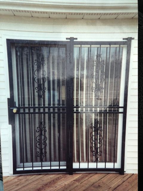 Black metal security gate over a doorway with white siding behind it