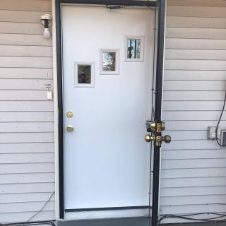 White exterior door with three small windows and brass knobs on a house porch
