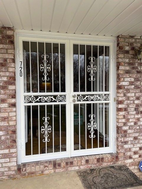 White security door and barred windows on a brick house porch, with address 720 visible.
