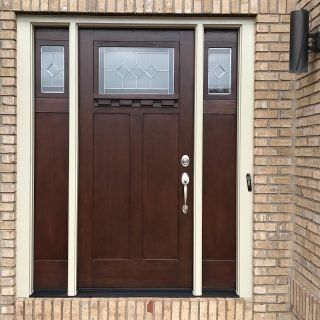 Dark brown front door with frosted glass sidelights in a brick entryway