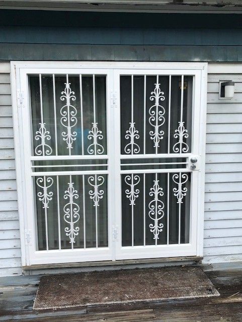 White metal security door with decorative bars on a house exterior