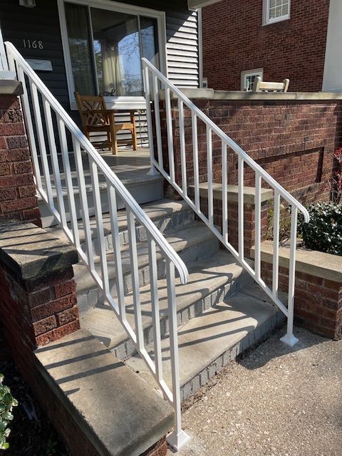 Front porch steps with white metal railings leading to a brick house entrance