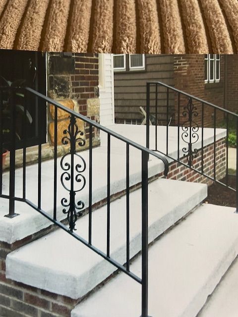 Black metal handrail beside white concrete steps leading to a brick building entrance
