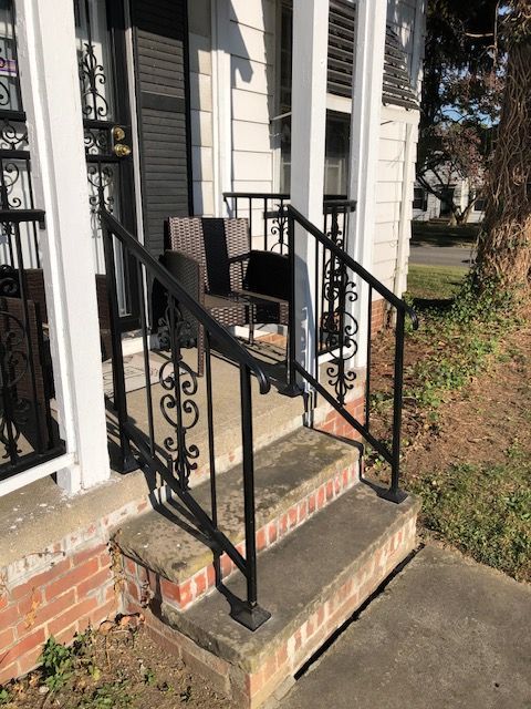 Front porch steps with black railings and a small ramp at a house entrance