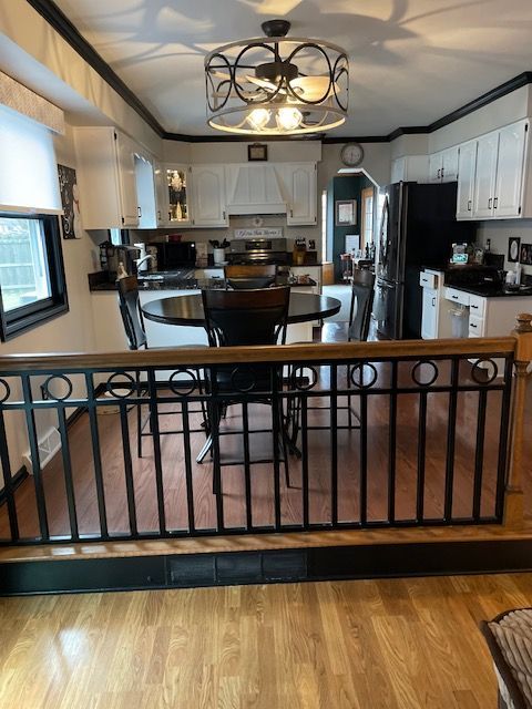 Kitchen and dining area with black-and-white cabinets, a round table, and a wrought-iron railing in the foreground