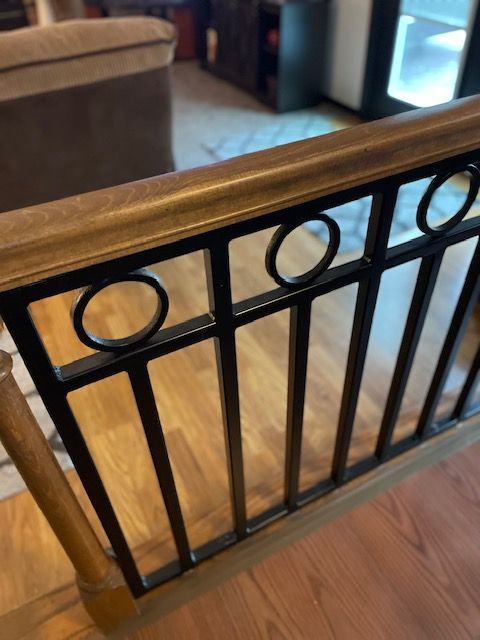 Black metal stair railing with circular accents over a wooden floor in a home interior