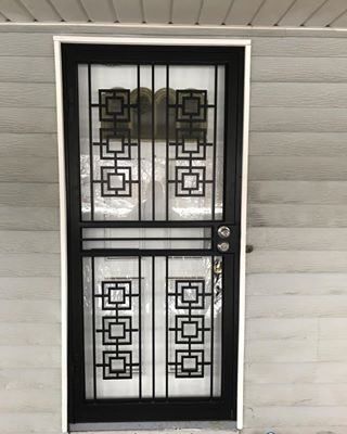 Black metal security door with decorative square patterns on a house exterior.