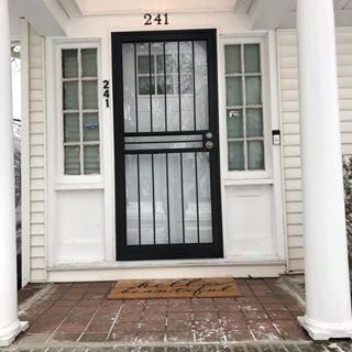 Front porch with white columns, black security door, and house number 241.