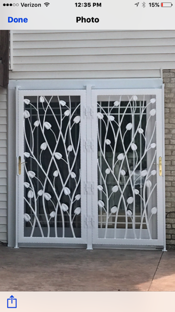 White double security gate with leaf-pattern bars in front of a house exterior