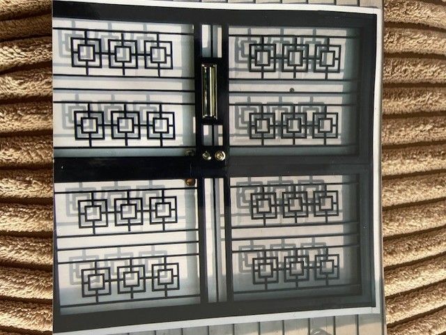 Black metal security gate with geometric pattern over a doorway or window