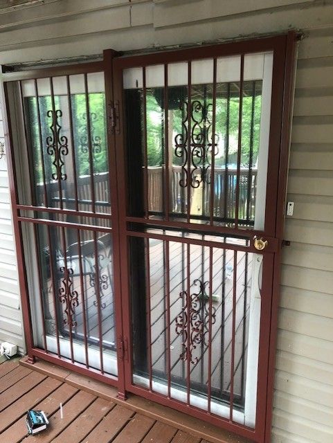 Brown metal security screen door over a glass sliding door on a porch
