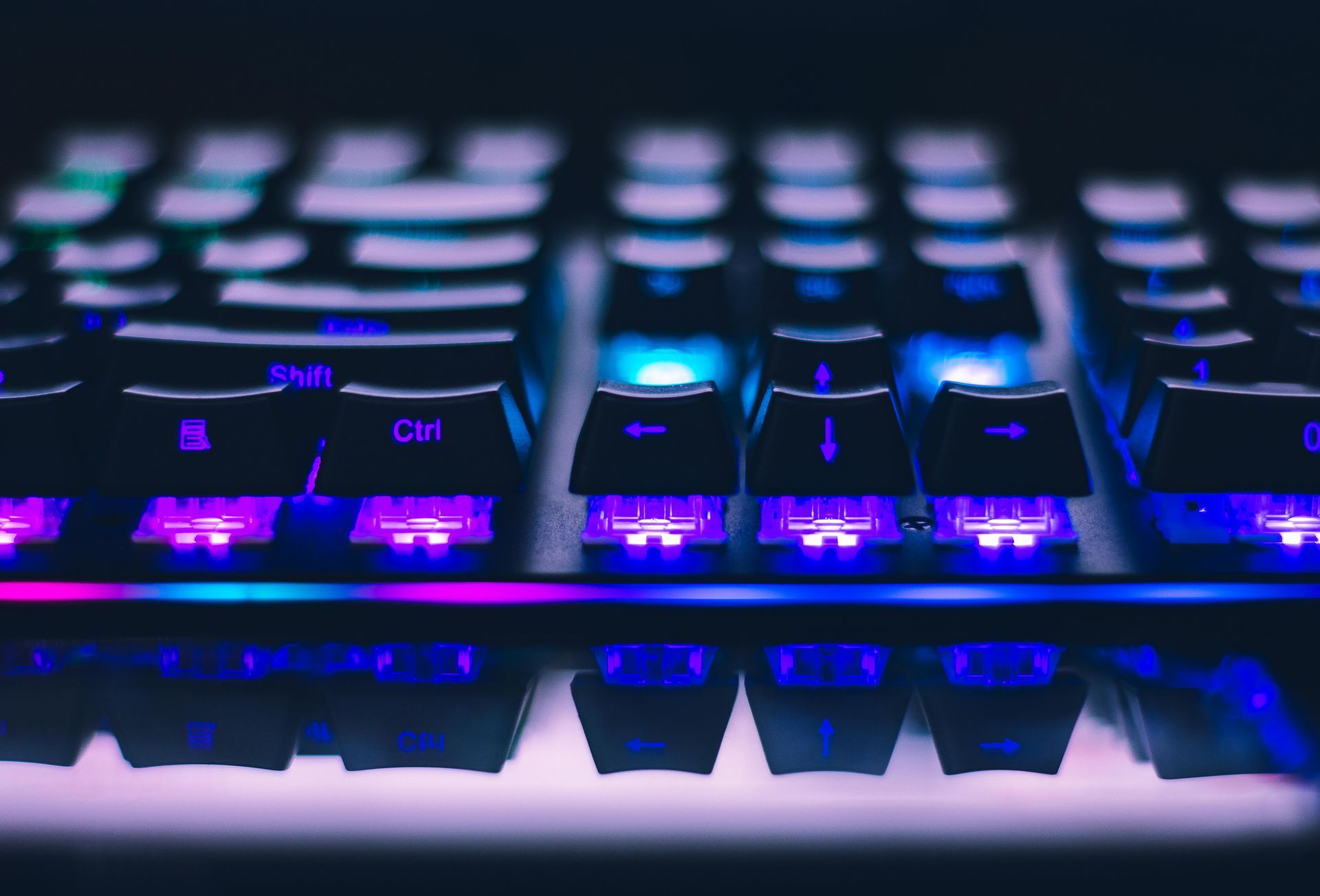 Illuminated purple and blue gaming keyboard keys in a dark close-up.