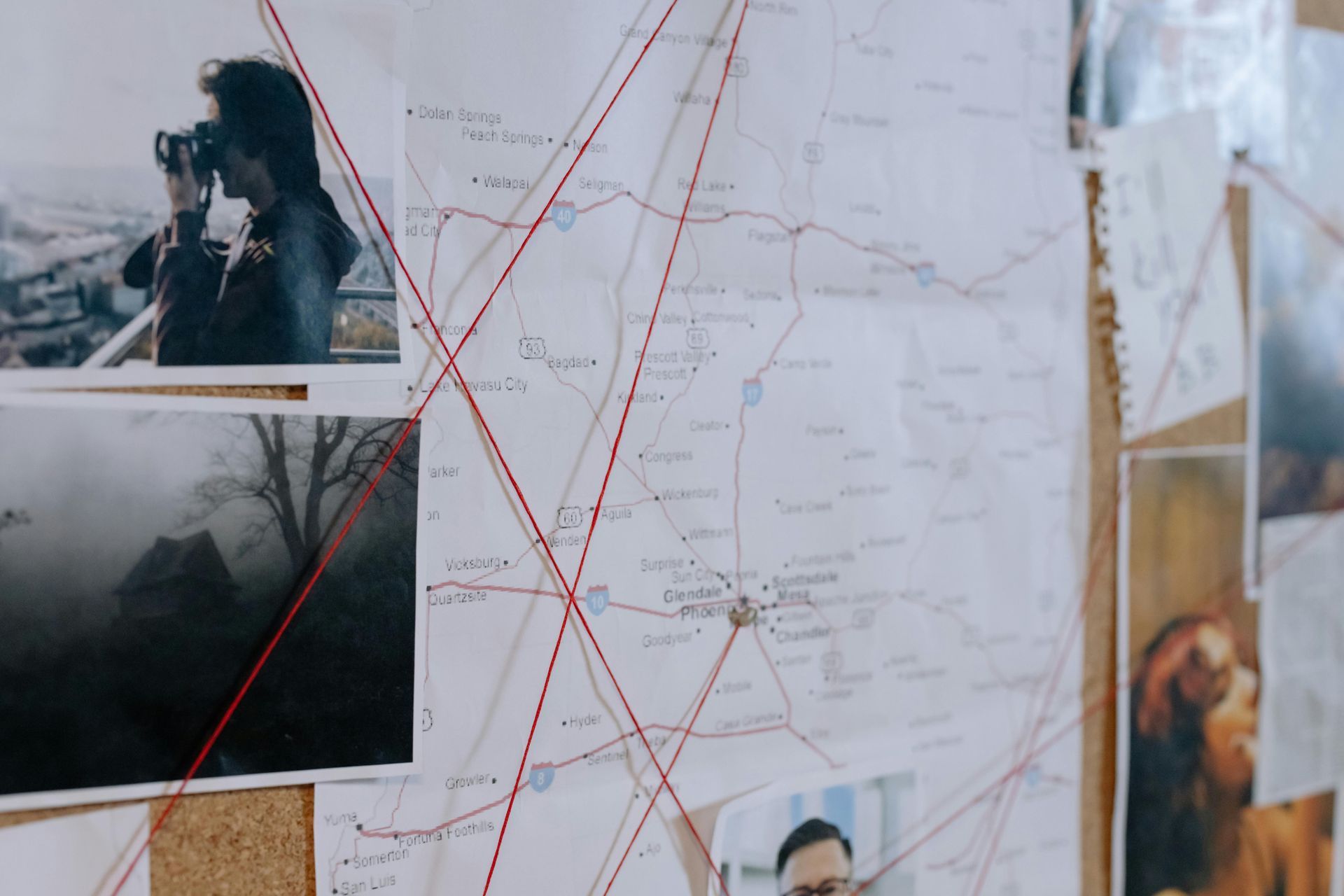 Crime investigation board with map, photos, and red string connections