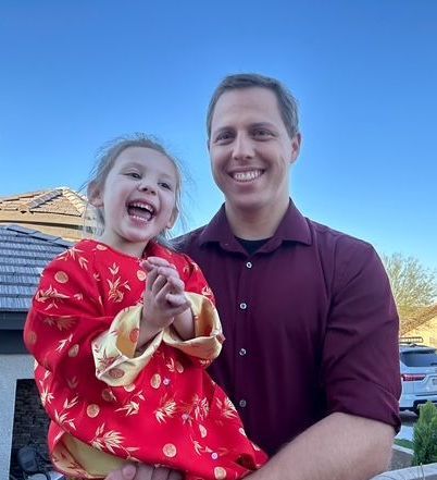 Man holding a laughing child, both smiling. 