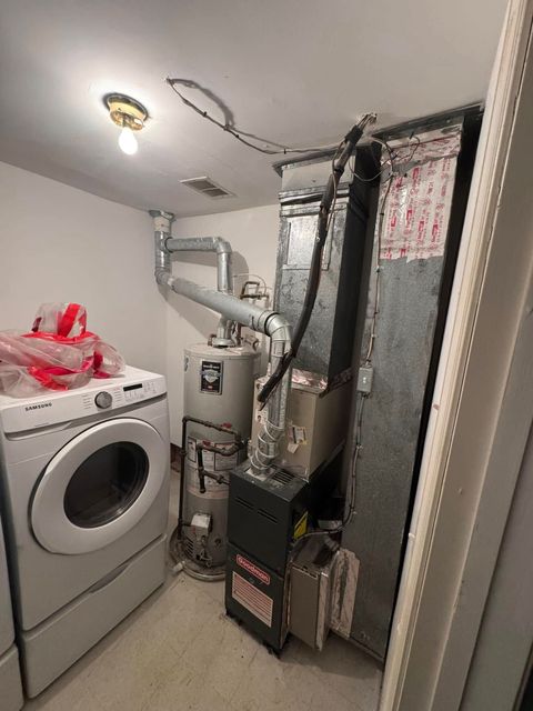 A laundry room with a washer and dryer , a water heater , and a furnace.