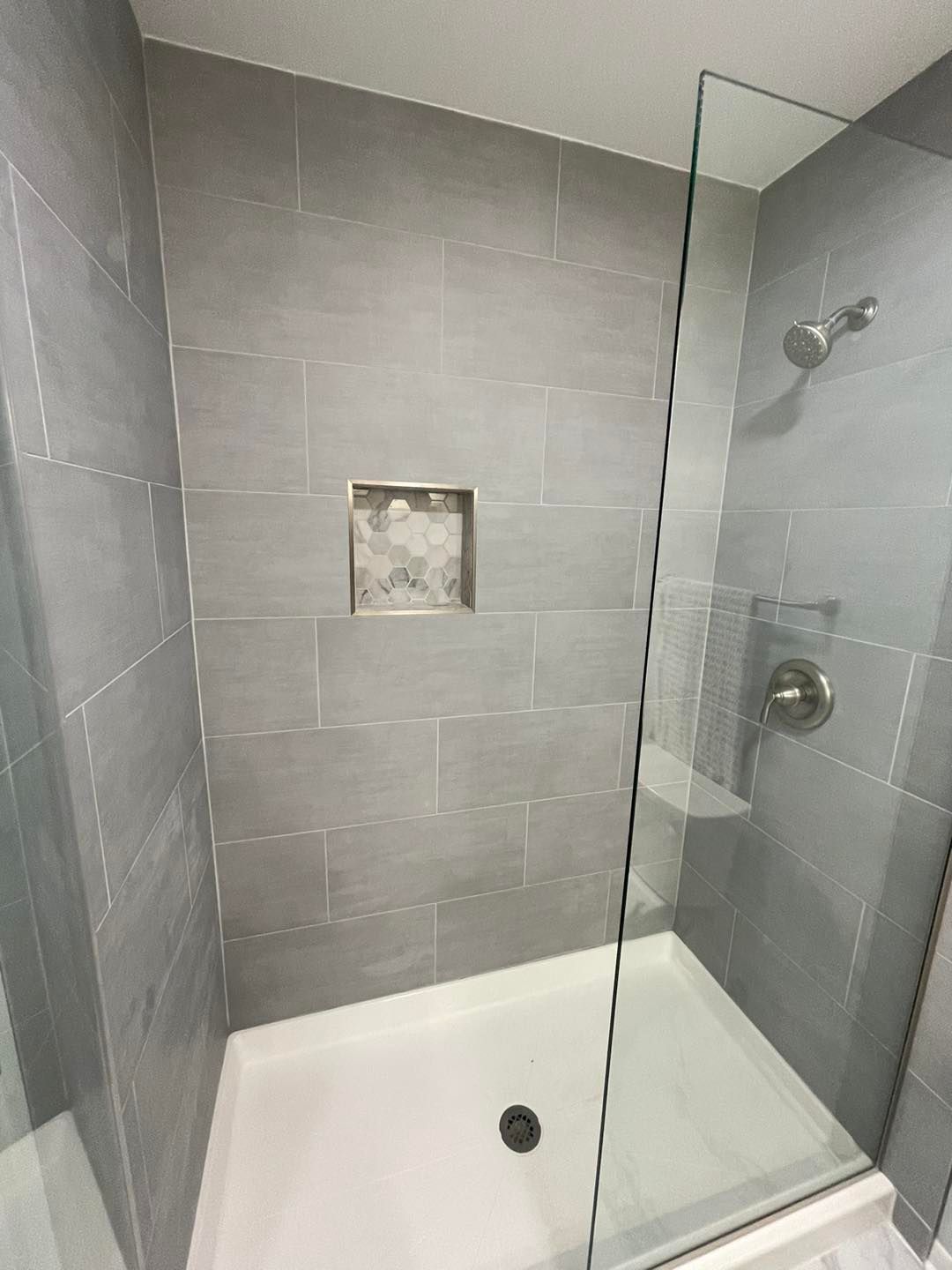 A bathroom with a walk in shower with a glass door.