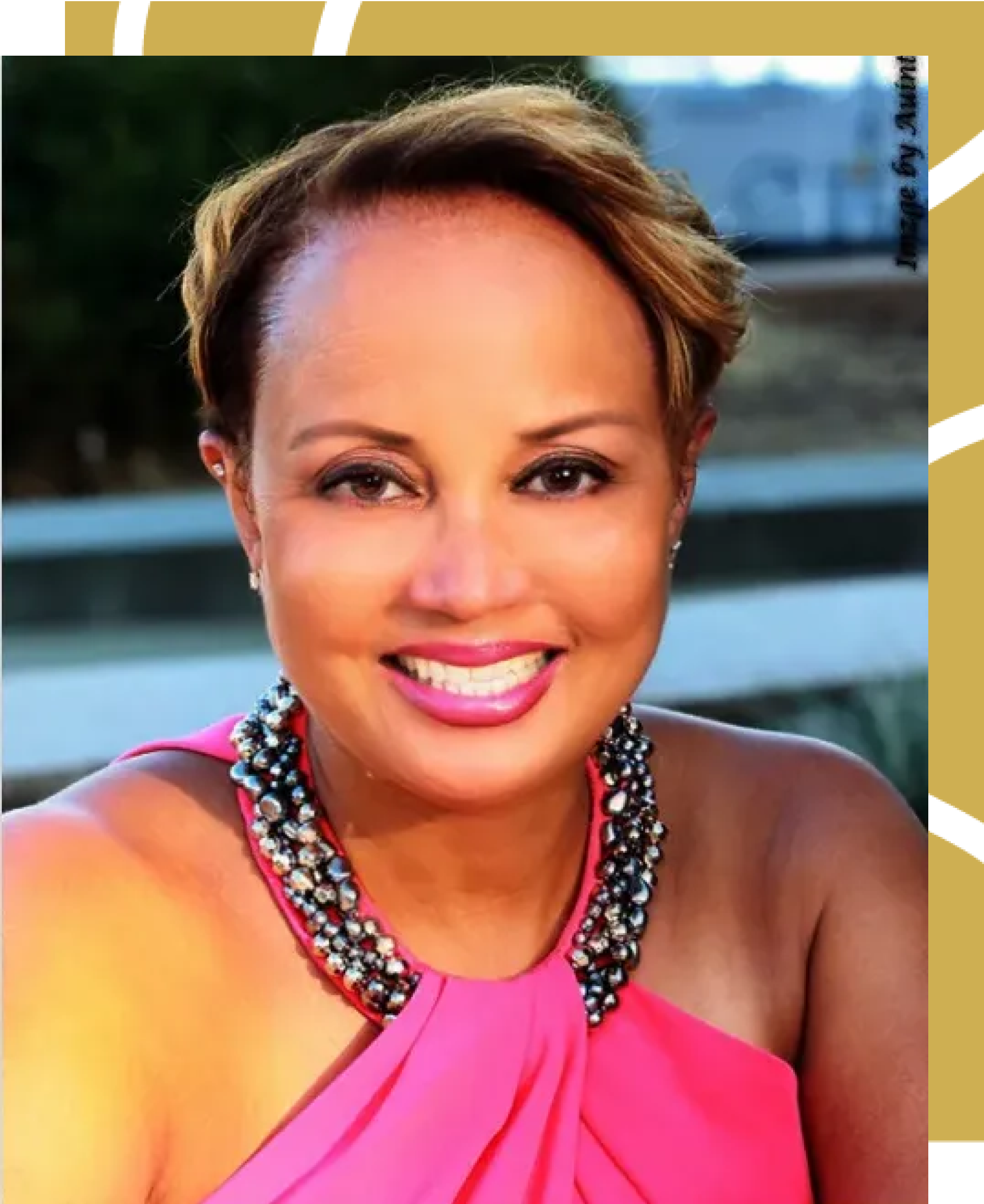 A woman in a pink dress and necklace smiles for the camera
