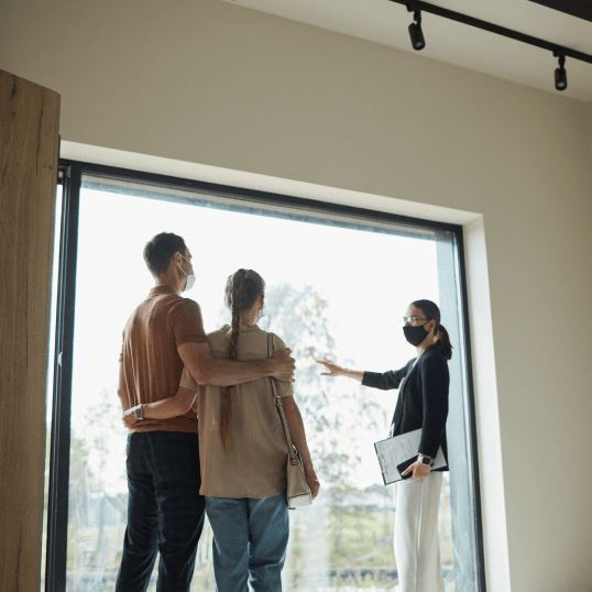 A man and a woman are standing in front of a window looking out.