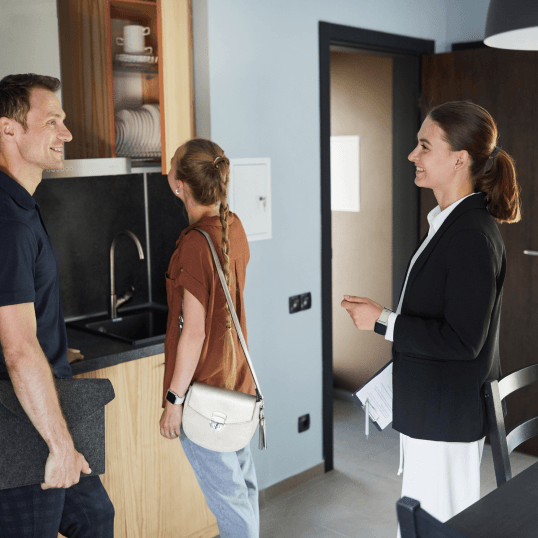 A woman is talking to a man and a woman in a kitchen