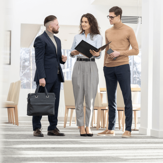 Three people are standing in a hallway talking to each other.