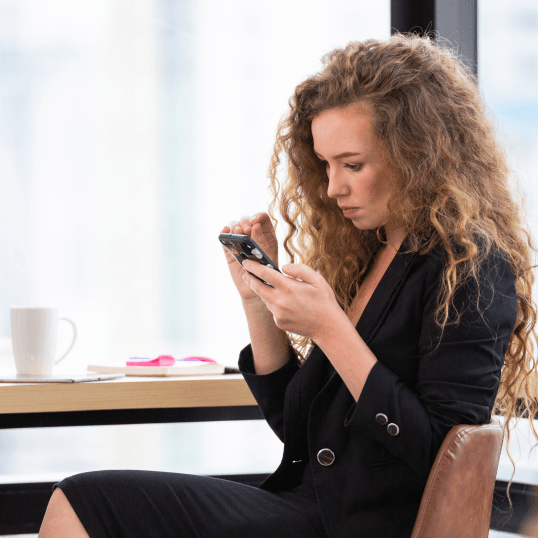 A woman is sitting at a table looking at her phone