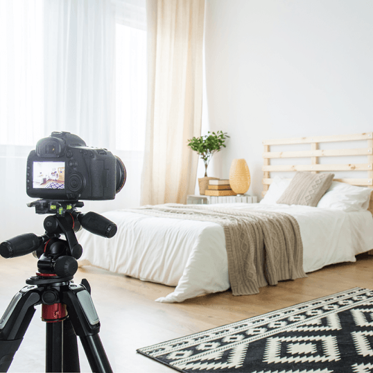 A camera is on a tripod in front of a bed in a bedroom