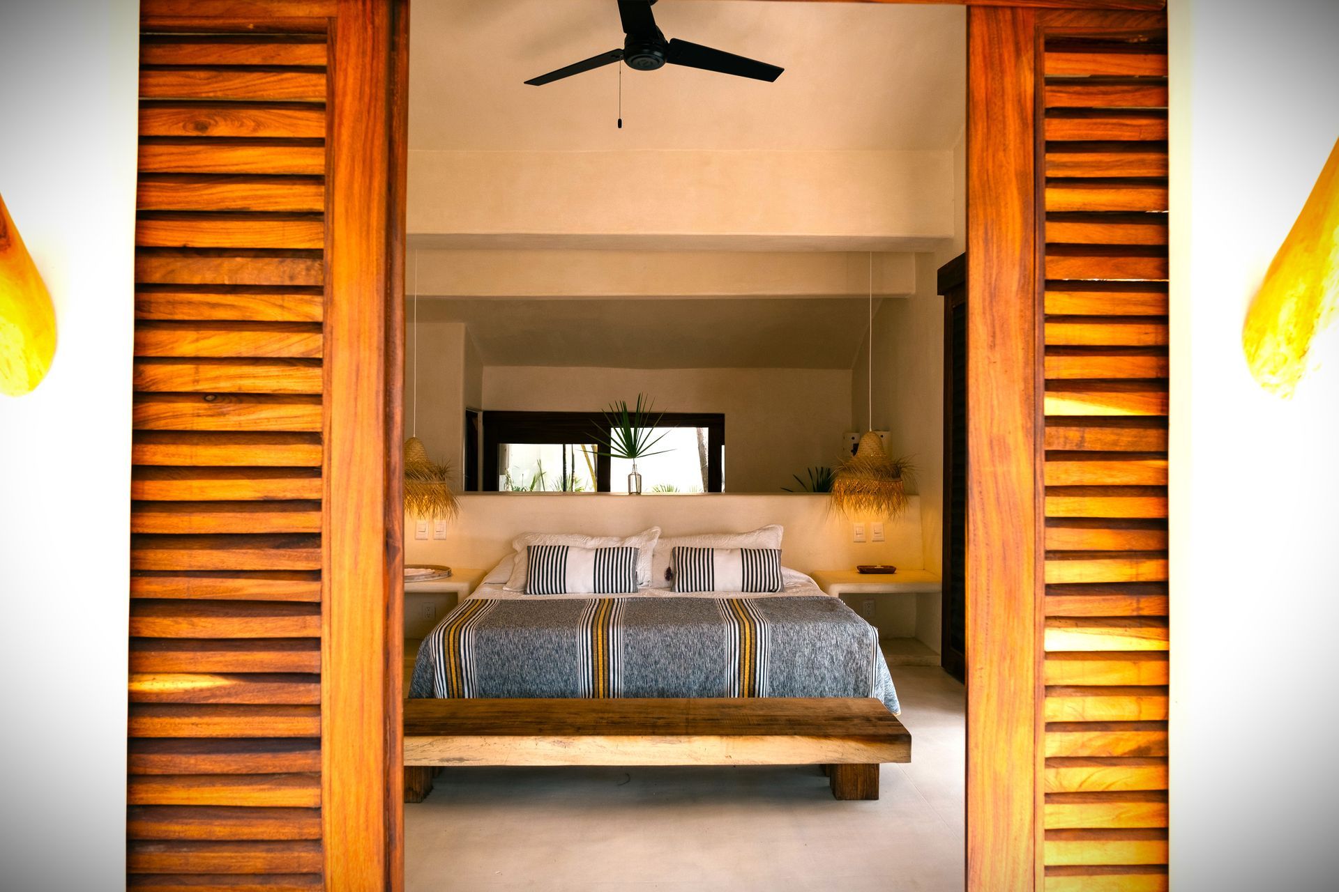 Interior de dormitorio con puertas de madera que se abren y revelan una cama con ropa de cama azul y blanca.