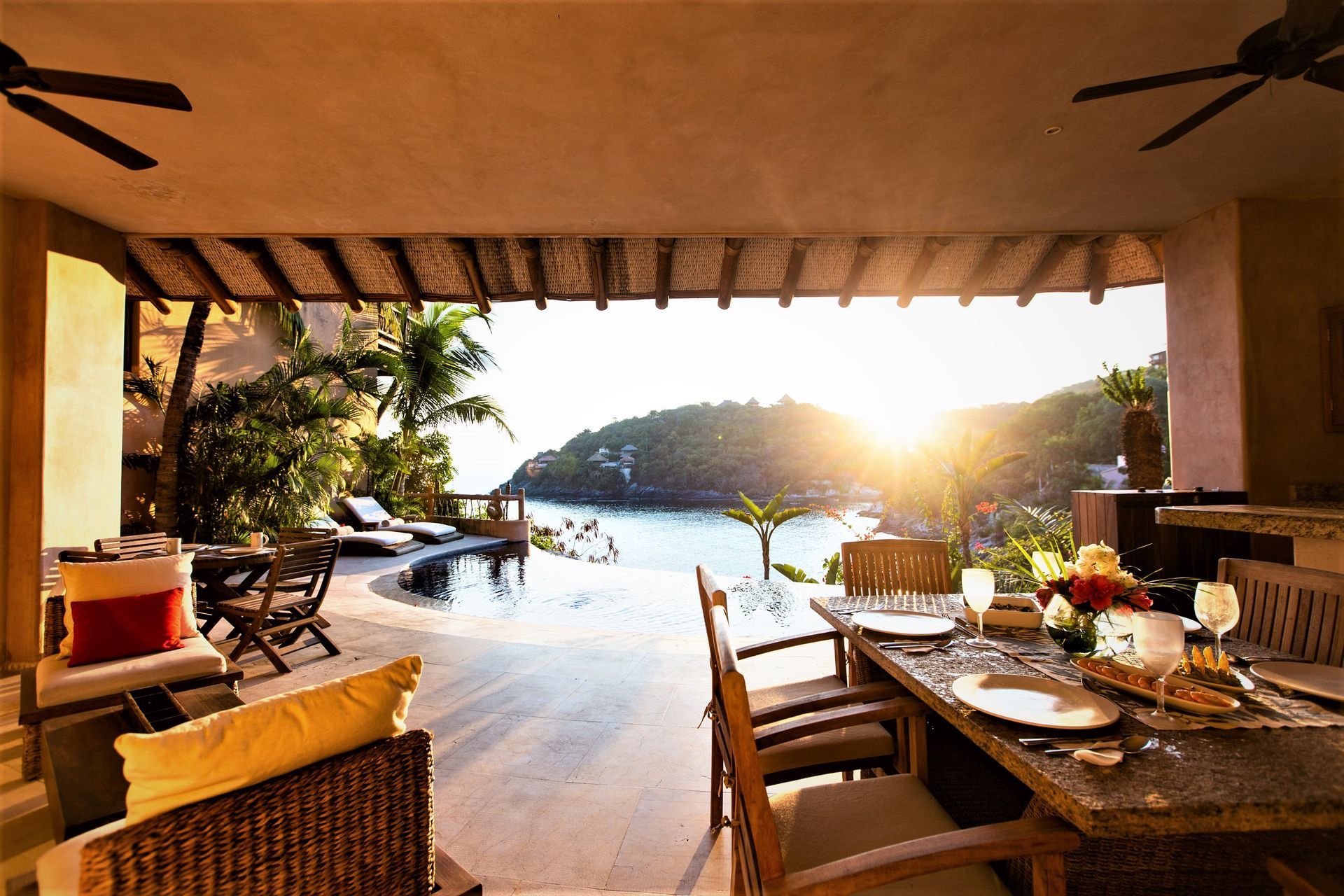 Comedor en el patio con vista al mar y a la piscina al atardecer.