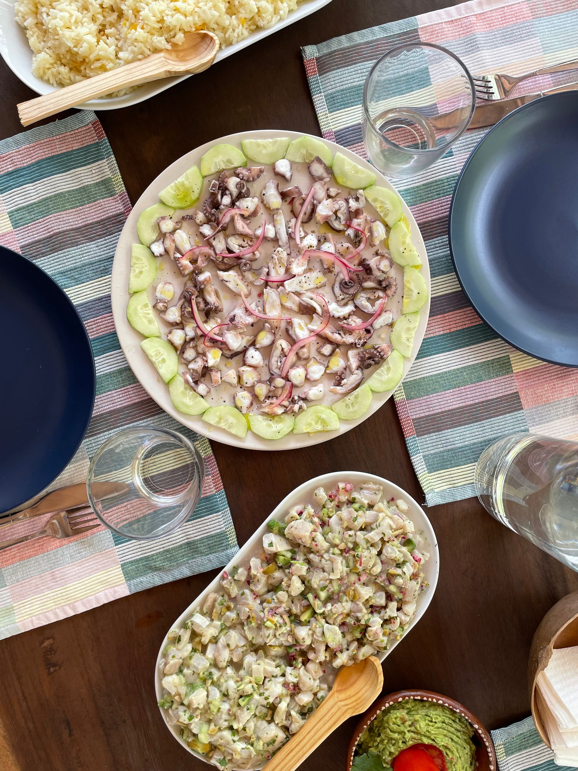Montaje de mesa con ceviche de pulpo, guarnición y platos azules.
