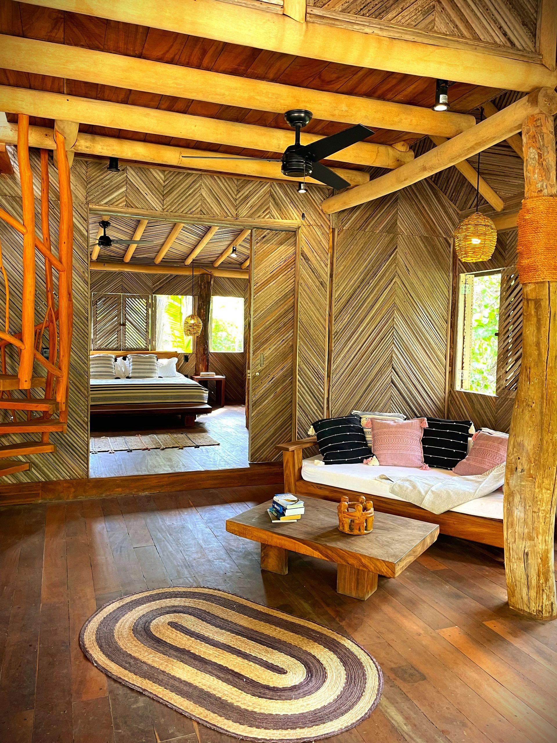 Acogedor interior de cabaña de madera con sala de estar y escalera de caracol, sala con texturas naturales y tonos cálidos.